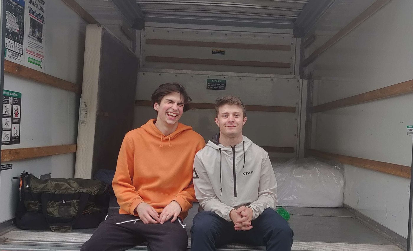 Joshua and a Tranquil Movers crew member sitting at the back of a truck
